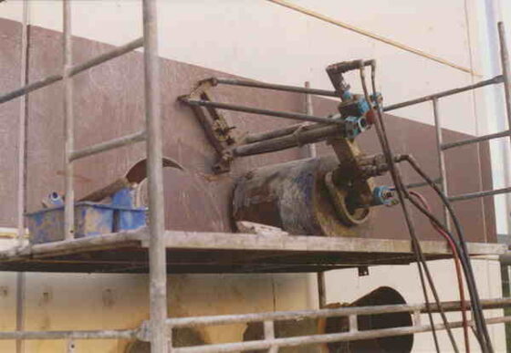 Hydraulisches System einer Maschine, montiert auf einem Gerüst, mit sichtbaren Rohren und Anschlüssen.