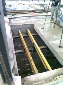 Bauarbeiten mit Holzträgern, die über eine Öffnung in einem Betonboden verlaufen.